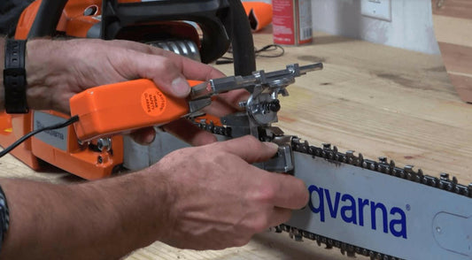 Bar-mount chainsaw sharpener clamped to a Husqvarna guide bar, one of the main types of chainsaw sharpeners for field use